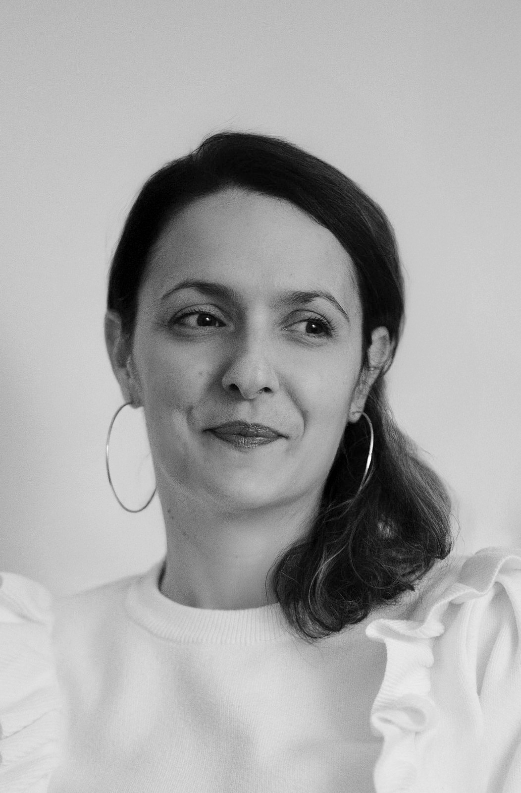 Portrait d'Émilie Missali en noir et blanc, assise de trois-quart et souriante.